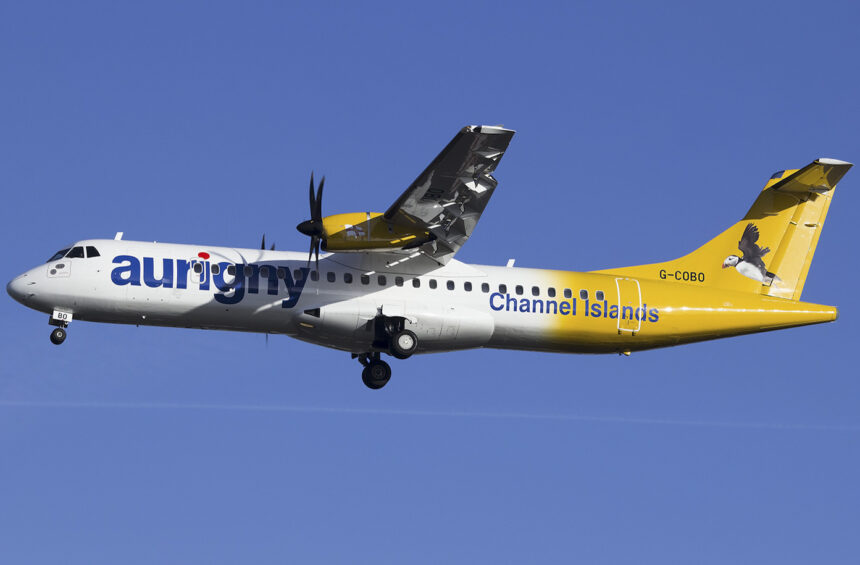 An Aurigny Air Services plane ascending into a bright blue sky.