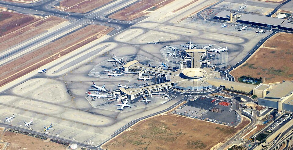 An overview of Ben Gurion Airport (TLV). The airport's main building can be seen at the centre of the surrounding runway, land and parked aircraft.