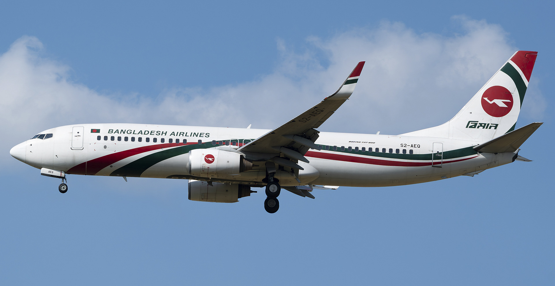 A Biman Bangladesh Airlines Boeing 737 mid-flight, with a blue sky with clouds in the background.