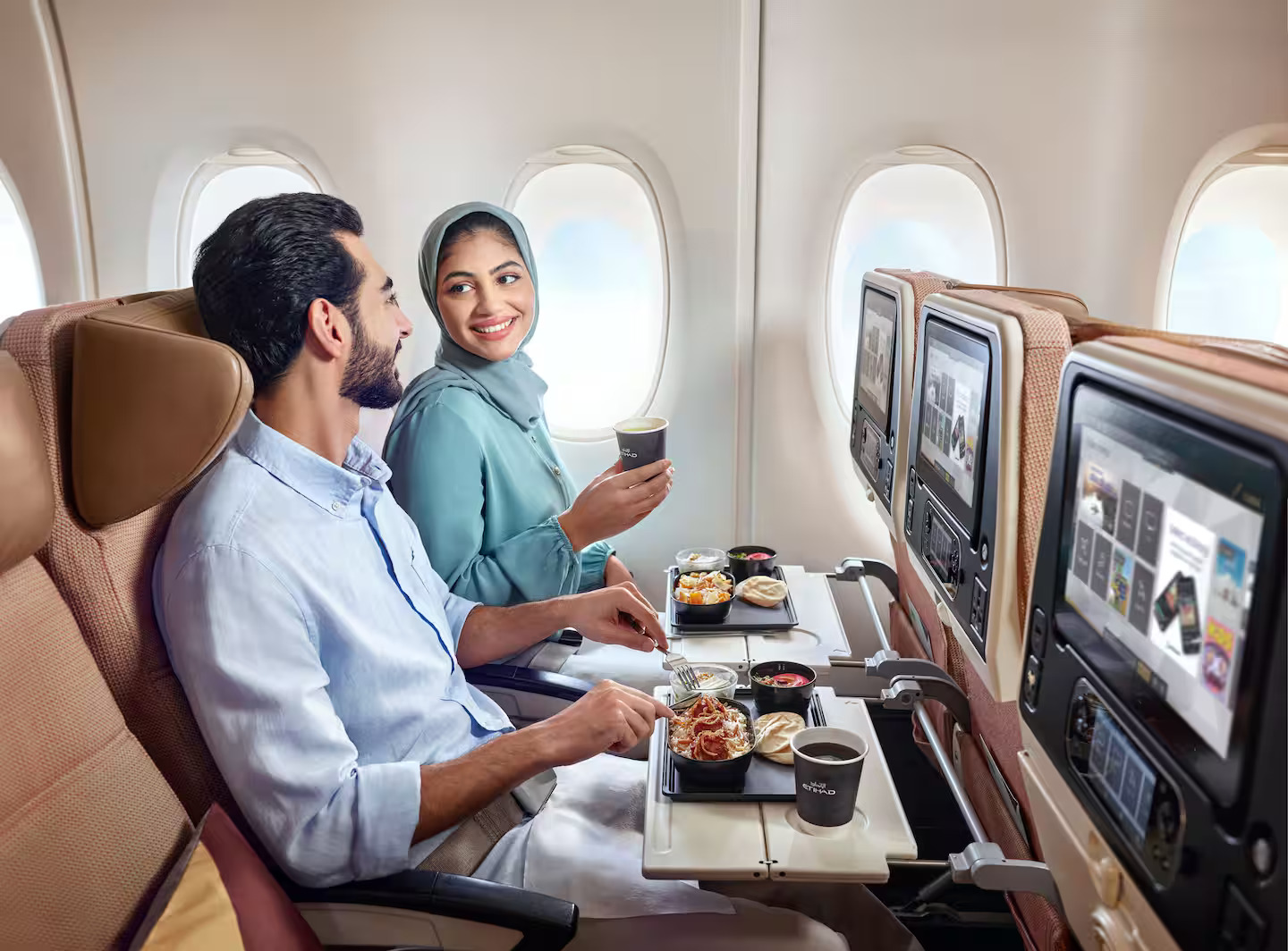 Photograph depicting the interiors of Etihad's Economy Class cabin with overview of seats and in-flight entertainment screen. 