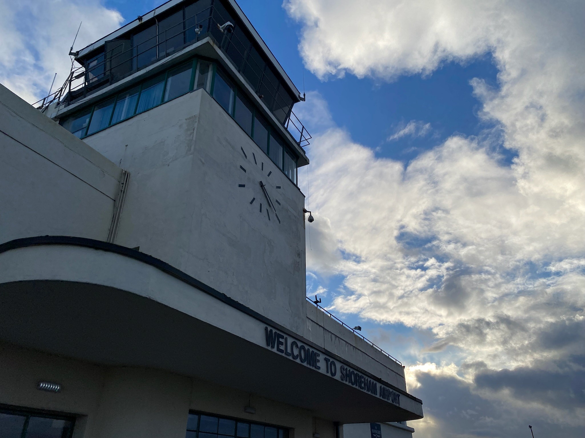 Image shows BCA's control tower from the ground up, with clouds in a blue sky