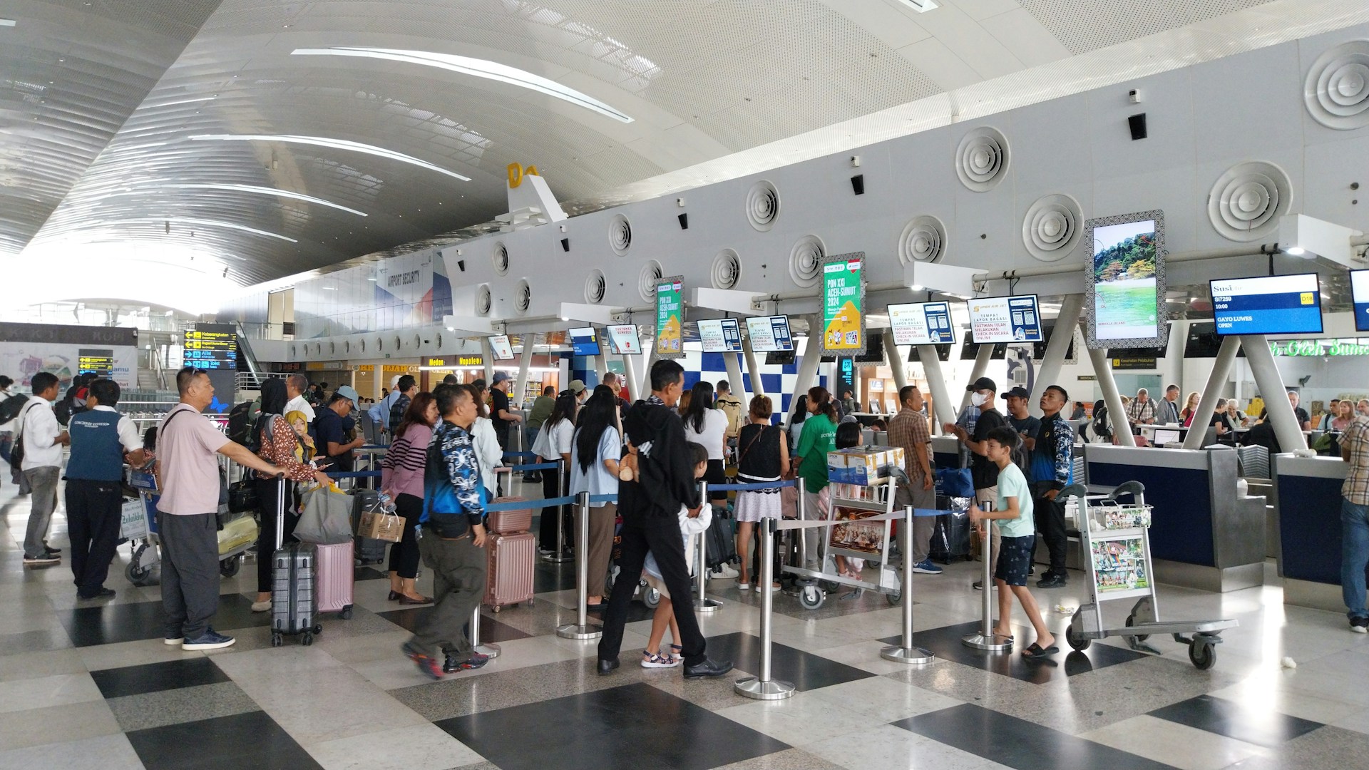 Passengers waiting in line with their luggages in Kualanamu International Airport