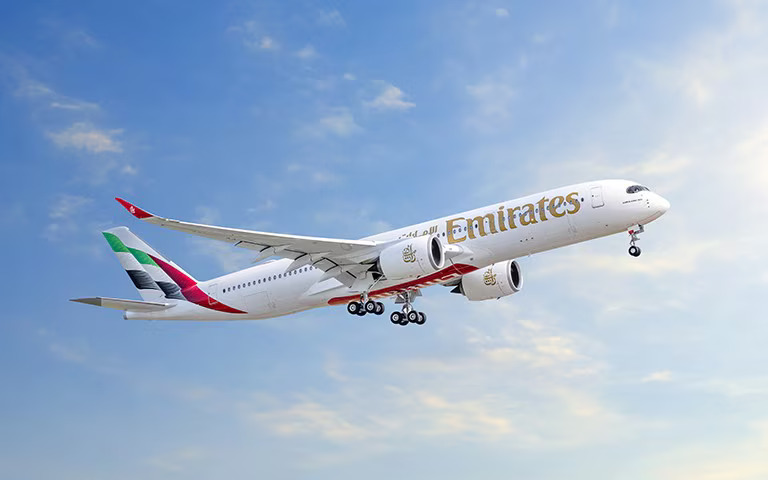 Photograph depicting the Emirates Airbus A350 flying above the clouds during daytime.