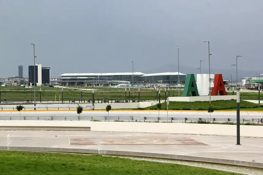 Felipe Ángeles International Airport (AIFA) terminal stands beyond a landscaped area, with large green, white and red letters on a mound under a grey, overcast sky.