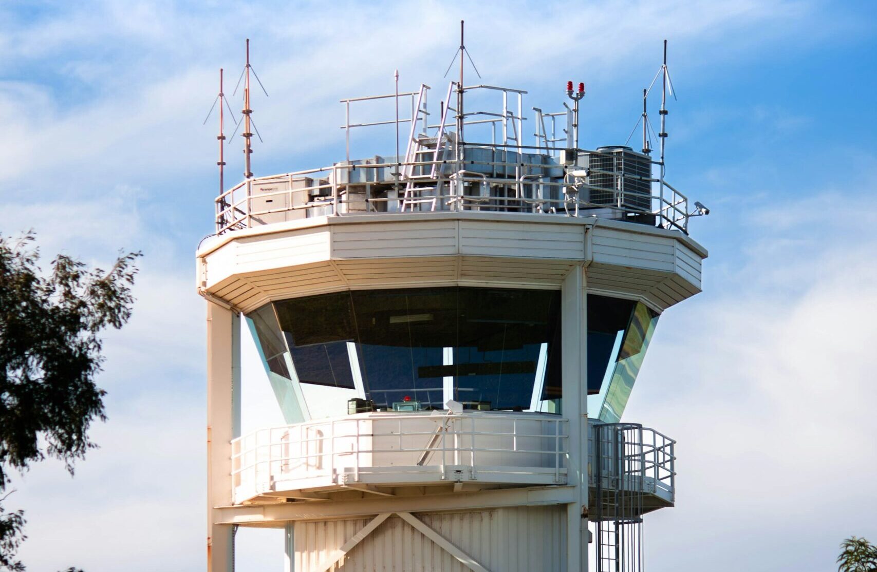 The top of an Air Traffic Control tower with blue skies and clouds in the background