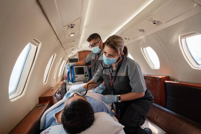 Two healthcare workers with AirLink providing care to a patient inside an AirLink air ambulance aircraft.