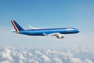 Image shows a blue branded ITA Airways aircraft in a blue sky with white clouds below