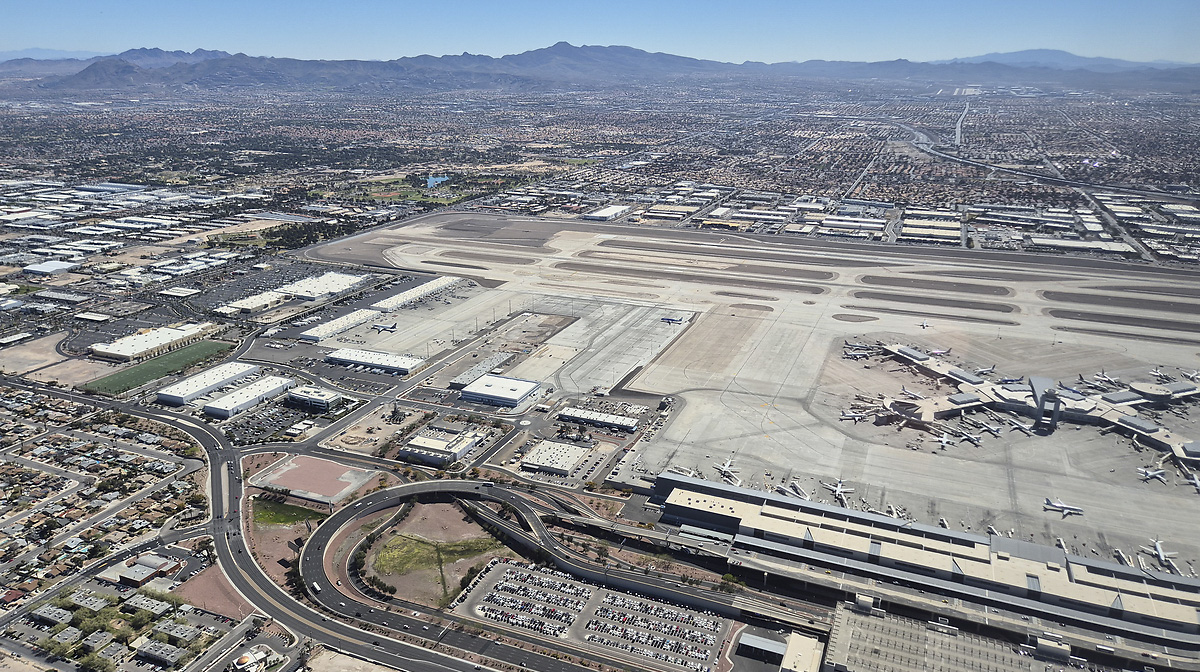 An aerial shot of Harry Reid International Airport in Las Vegas, showing the stretch of its runway and several planes surrounding its main terminal.