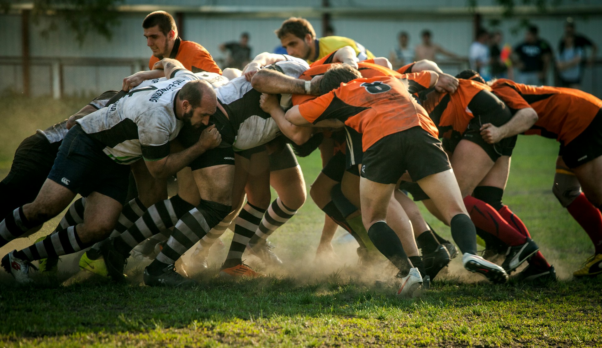 Rugby players in a scrummage with white and orange shirts 