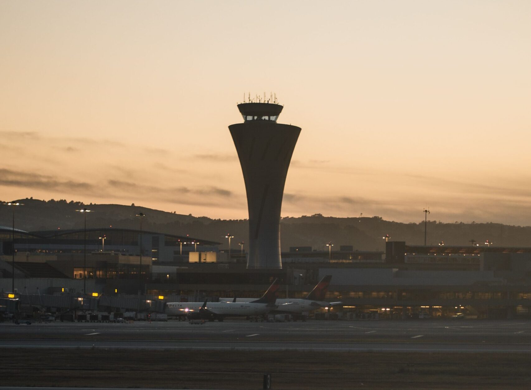 Silhouette of control tower at San Francisco Airport during sunset, capturing aviation mood.