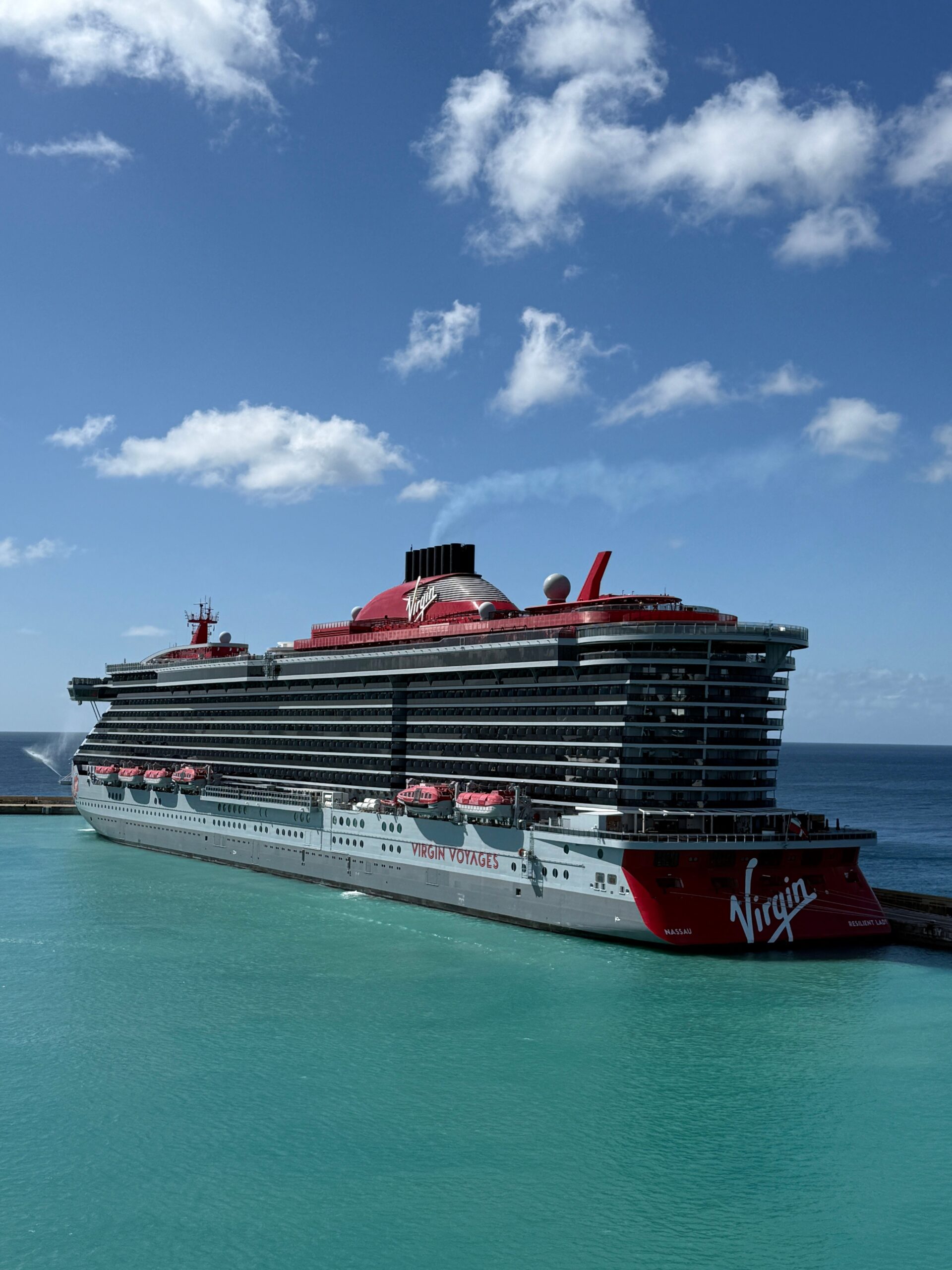 Brilliant Lady cruise, Virgin Voyages docked in a stunning blue ocean port under a clear sky. © Sergii