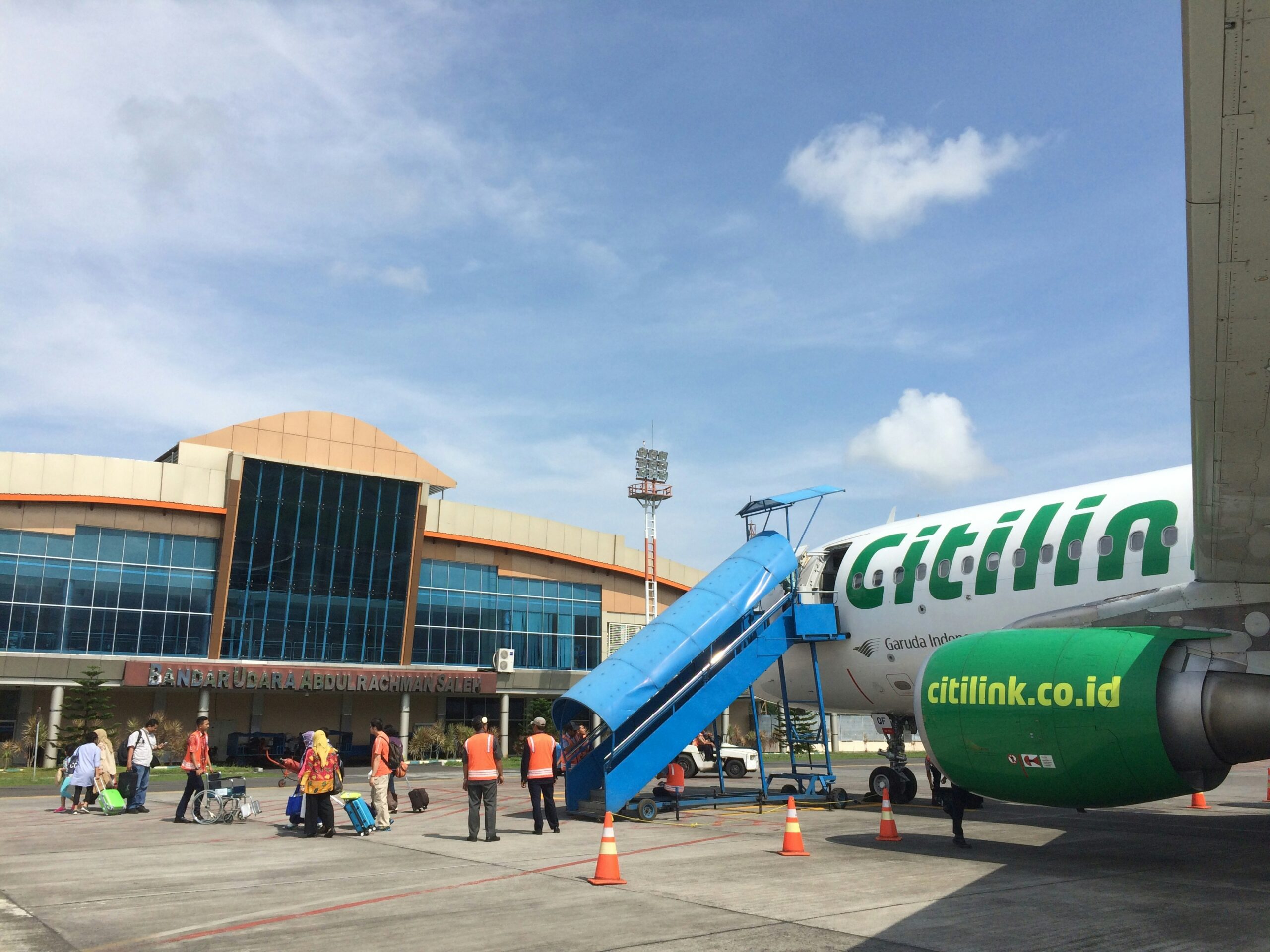 A Citilink aircraft on an airport tarmac with stairs to the aircraft
