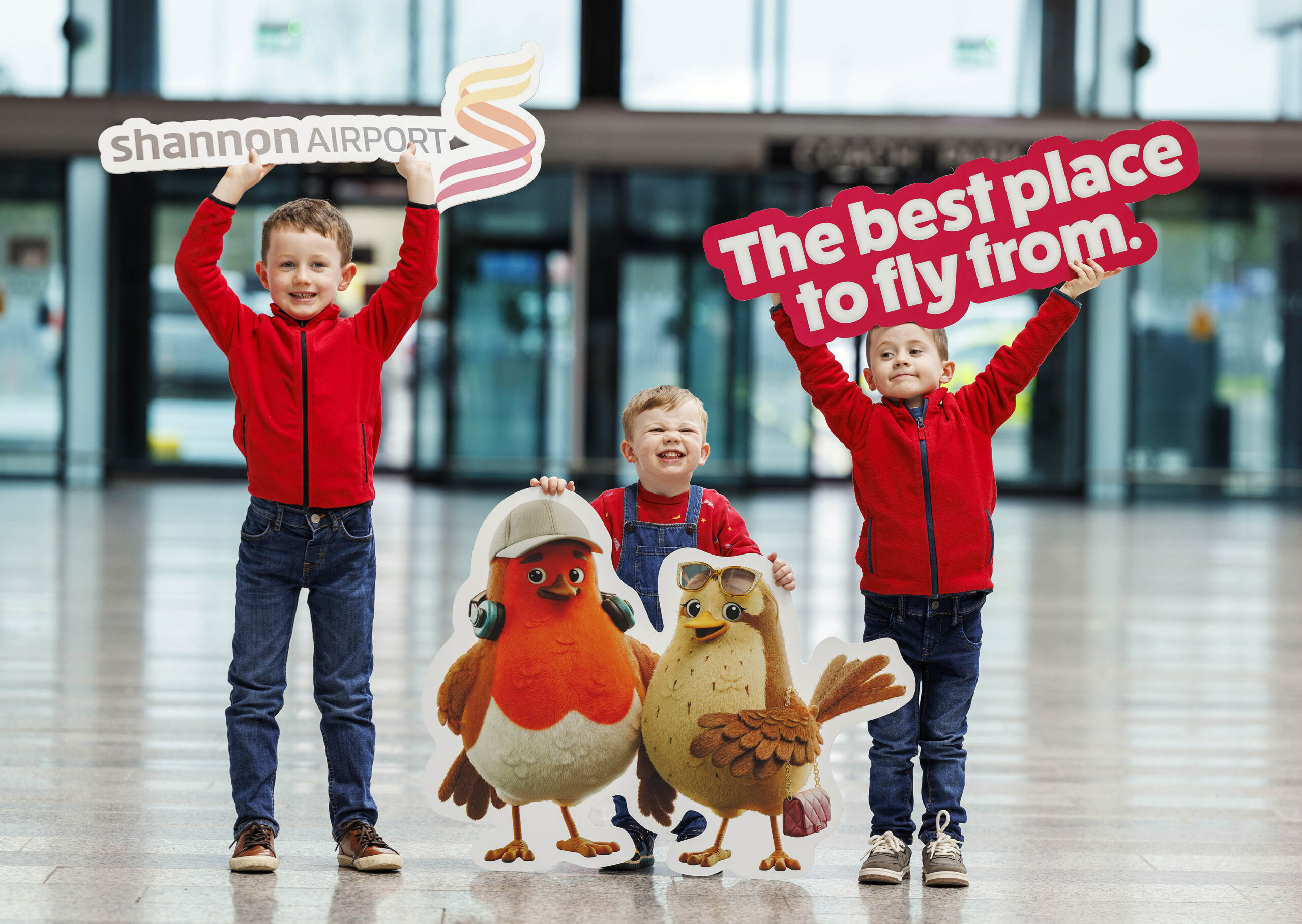Image shows three young male children with banners and promotional bird characters for Shannon Airport 'The best place to fly from'