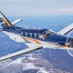 Photo of a Daher aircraft in the sky above the sea facing eastwards