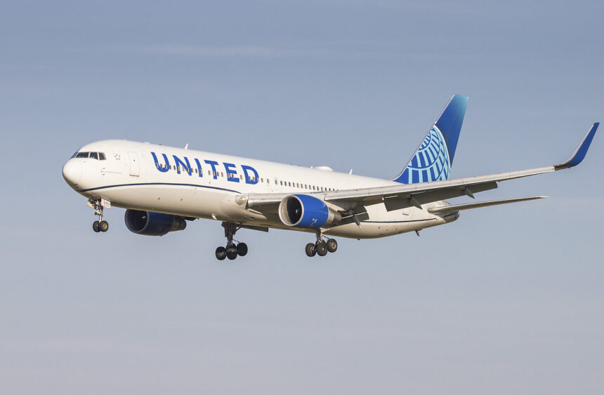 A United Airlines Boeing 767 pictured mid-flight with a blue sky in the background.
