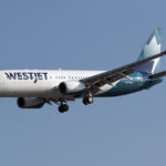 A WestJet Boeing 737 mid-flight with a blue sky as the background.